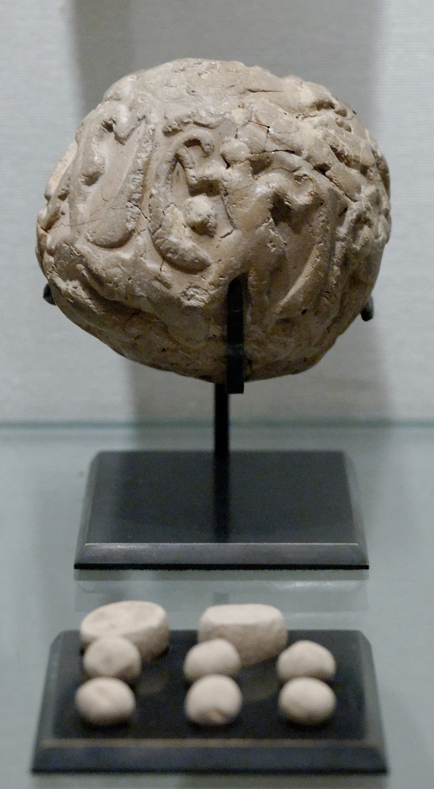 Sealed clay envelope and tokens in a museum display, Susa; Louvre SB 1932, ca. 3500–2900 BCE according to the museum record. A recording device, not a written linguistic sentence